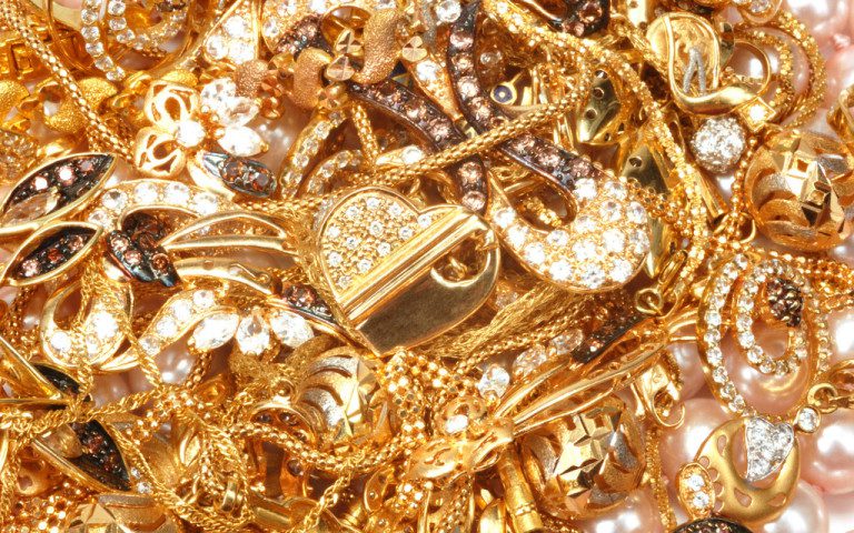 Background image of a pile of sparkling gold jewelry with diamond accents.