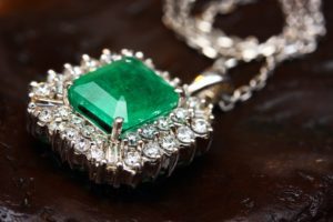 Image of an emerald laid within set diamond jewelry necklace