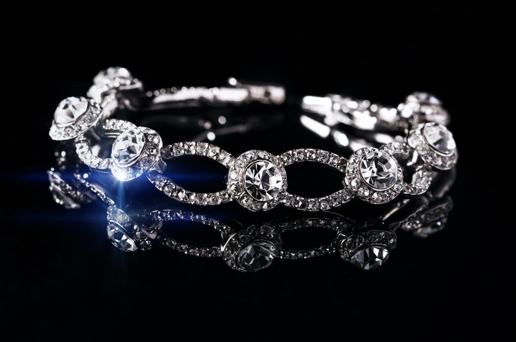 Image of a diamond bracelet sparkling on a black background.