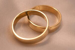 Image of two gold rings stacked on top of one another against a beige background
